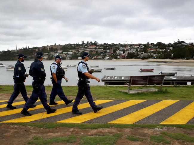 Police officers walk past an empty Rose Bay beach which was closed to the public on NYE this year. Picture: Toby Zerna