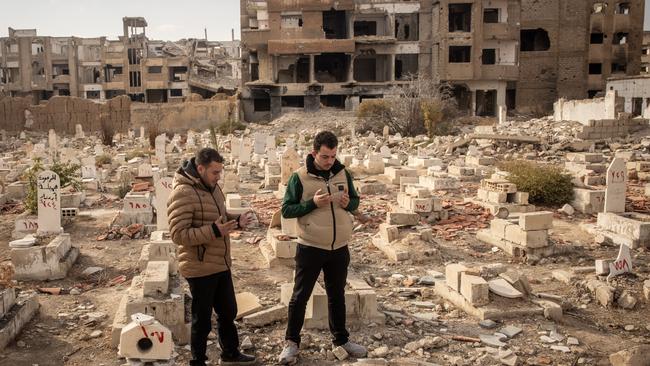 Ahmed Karkar, right, and his cousin pray over the damaged grave of his brother Ayman, who was killed by a Syrian army sniper, in Damascus on December 23. Picture: Getty Images