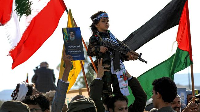 A man carries on his shoulders a young child holding an assault rifle and wearing military fatigues during a rally in the Houthi-controlled capital Sanaa in Yemen. Picture: AFP.