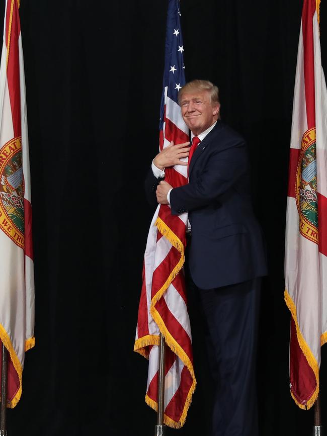 Getty Images Year in Focus 2016: Republican presidential candidate Donald Trump hugs the American flag as he arrives for a campaign rally at the MidFlorida Credit Union Amphitheatre on October 24, 2016 in Tampa, Florida. There are 14 days until the the presidential election. Photo by Joe Raedle/Getty Images
