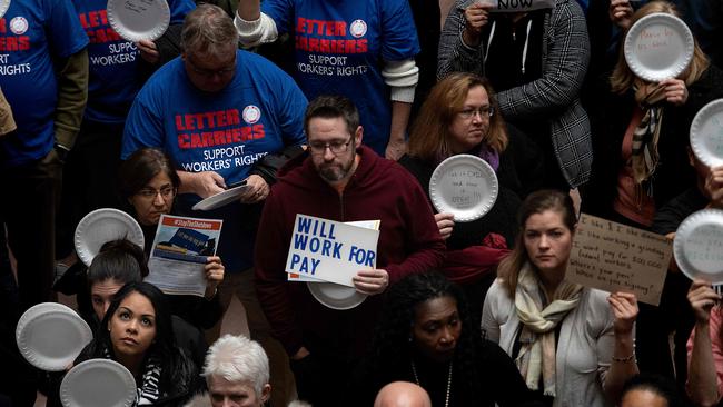 A federal worker stands with a placard reading "Will Work For Pay" as other federal employees stage a rally to call for a vote on the shutdown on Capitol Hill.