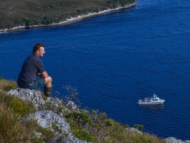 Pieter van der Woude takes a break atop Balmoral Hill, looking down on the Odalisque anchored in Port Davey.