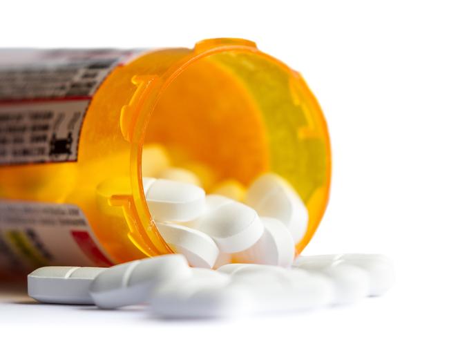 close up of a group of white tablets with an out of focus prescription bottle in the background