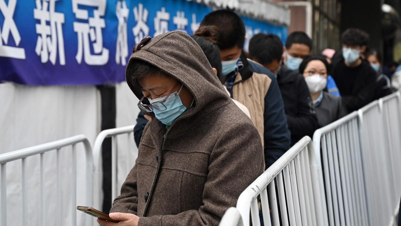 People line up to get a booster shot of the Covid-19 coronavirus vaccine in a tent set up outside a shopping mall in Beijing. Picture: Greg Baker / AFP