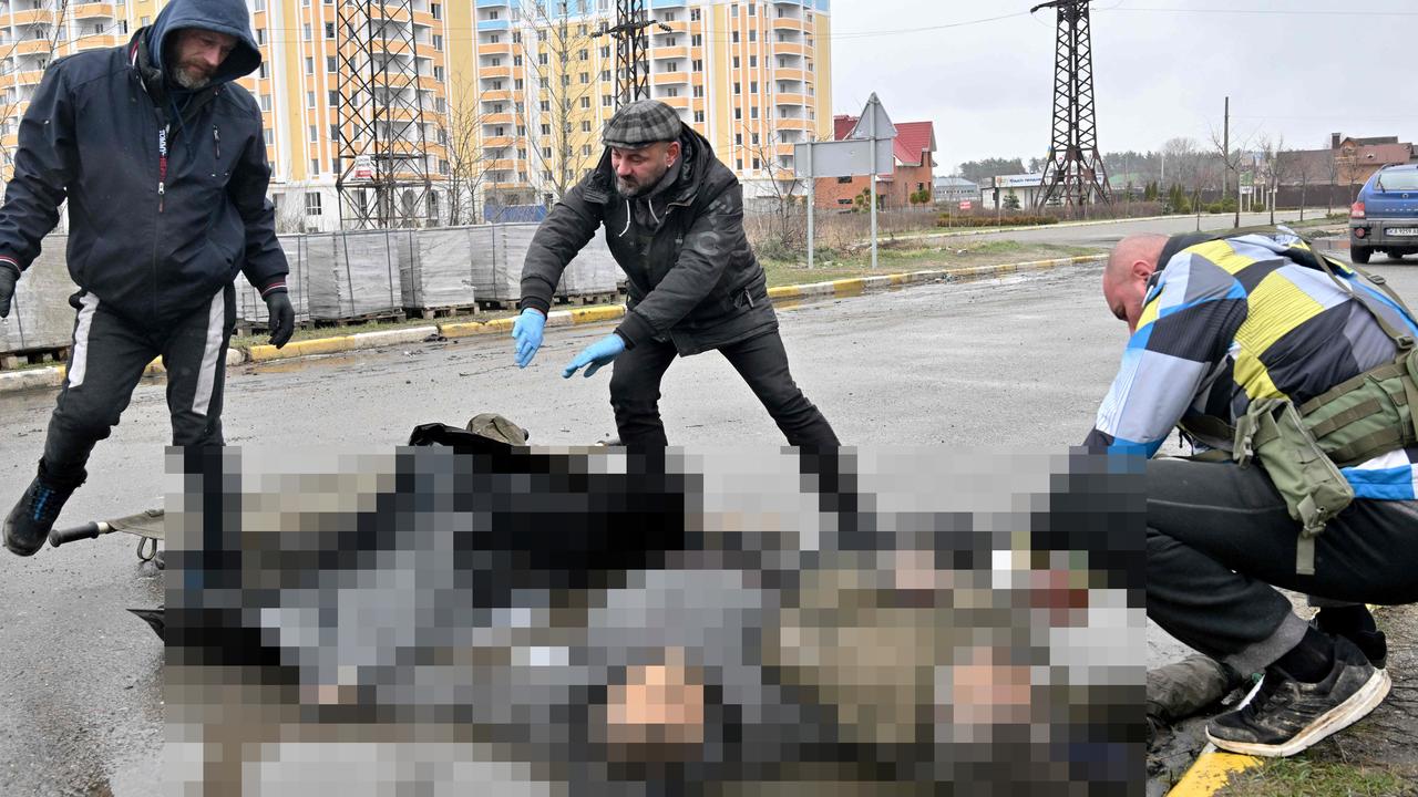 Ukrainian workers collect the bodies of two men in Bucha. Picture: Sergei Supinsky/AFP