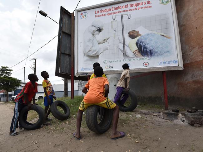 Children look at a poster warning of the dangers of the Ebola virus reading "the risk Ebola is still there. Let's apply the protective measures together". Picture: Sia Kambou