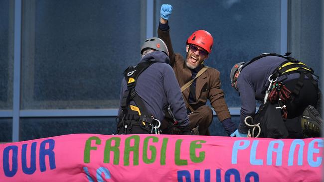 Police officers arrest an activist who scaled the roof of the entrance to London City Airport Picture: AFP