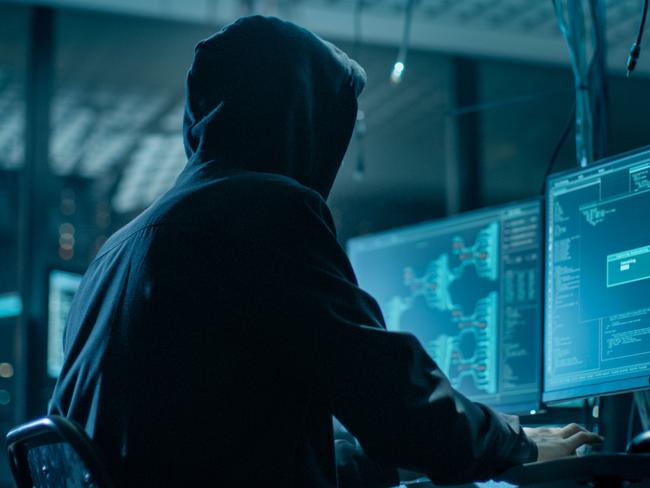 Shot from the Back to Hooded Hacker Breaking into Corporate Data Servers from His Underground Hideout. Place Has Dark Atmosphere, Multiple Displays, Cables Everywhere; scams, scammer generic