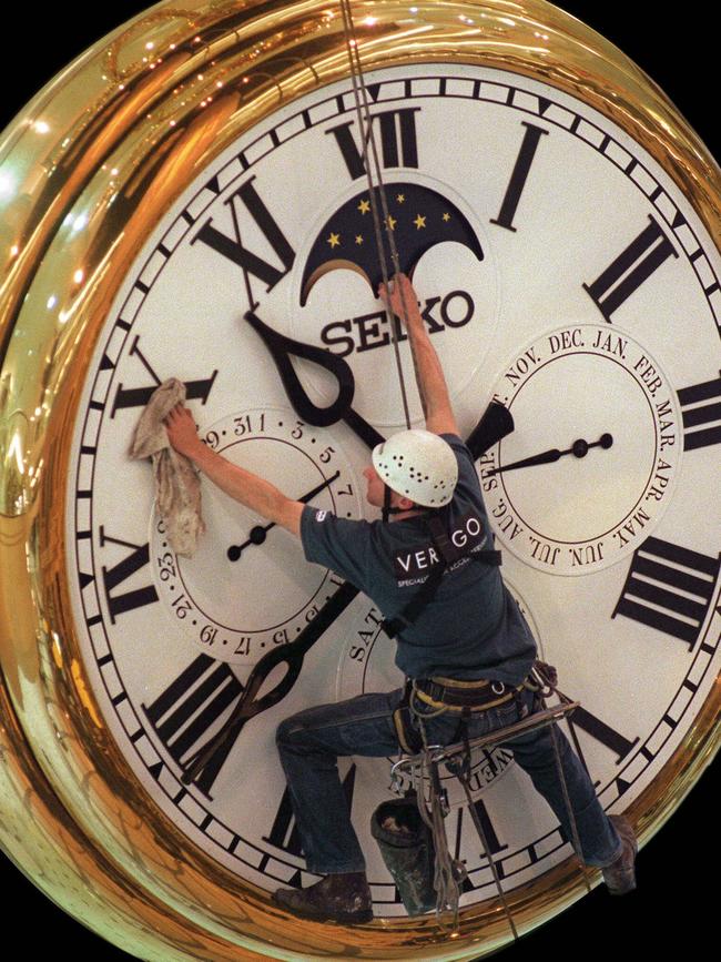 A worker cleans the large Daimaru clock at night.