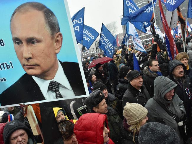 People hold a placard with the picture of the Russian President during a rally in support to Russian athletes this month. Picture: Vasily Maximov/AFP