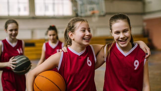 Cute teenage girls, smiling and hugging after basketball match, happy after winning the game