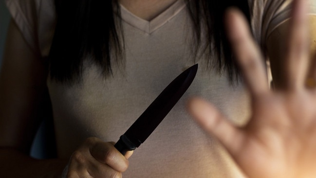 Woman holding a knife in hand while defending herself from attacks. Photo: iStock