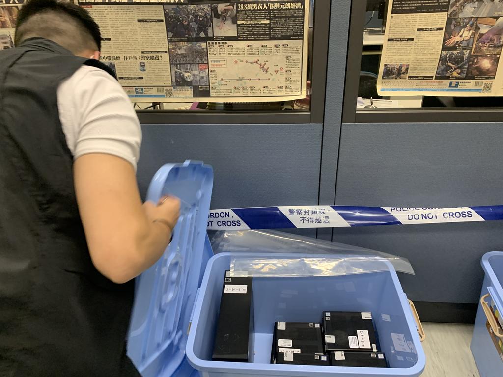 Police officers conduct a raid at the Apple Daily office.