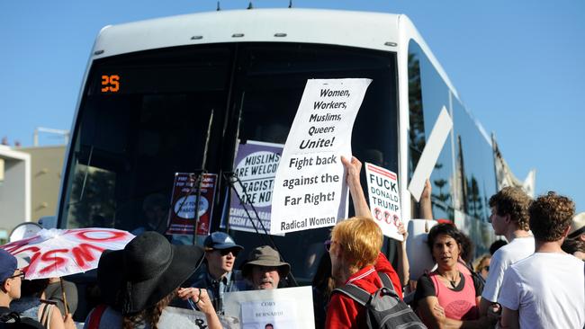 Protesters in front of a bus carrying Q Society supporters.