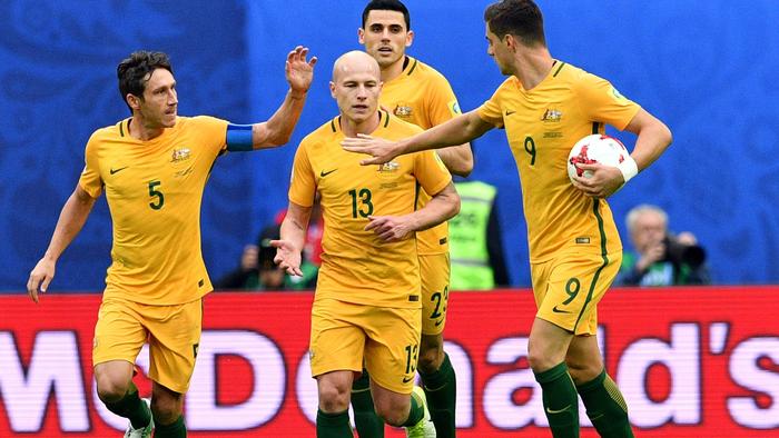 Australia's midfielder Mark Milligan (L) is congratulated by midfielder Aaron Mooy (C) and forward Tomi Juric afetr scoring in a penalty during the 2017 Confederations Cup group B football match between Cameroon and Australia at the Saint Petersburg Stadium on June 22, 2017. / AFP PHOTO / Mladen ANTONOV