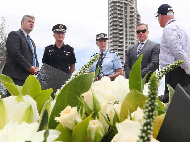 Police Minister Mark Ryan, QFES Commissioner Greg Leach, Police Commissioner Katarina Carroll, Deputy Premier Steven Miles and Adam Stevenson from QFES stand behind floral tributes placed at the memorial area for the helicopter crash victims at the Broadwater Parklands. Picture: Glenn Hampson.