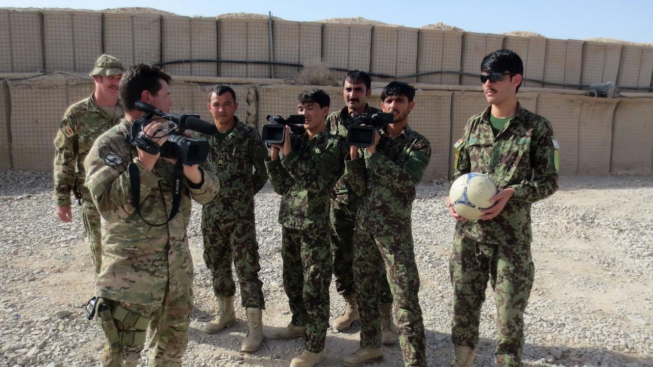 Corporal (CPL) Chris Moore (left with camera) instructing the Afghanistan National Army Soldiers how to use a video camera as part of his mentoring and training which he was tasked to conduct. Picture: Supplied