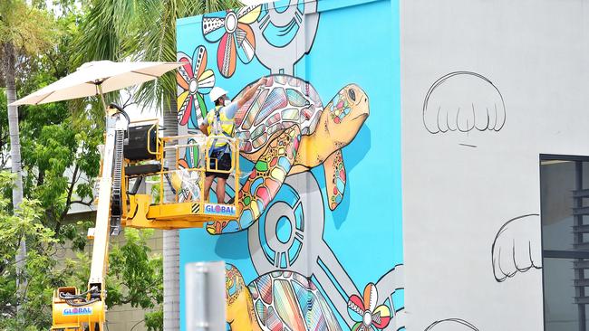 Darwin artist Hafleg puts the finishing touches to his street art mural which is on the side of the city police station. Picture: Shae Beplate.