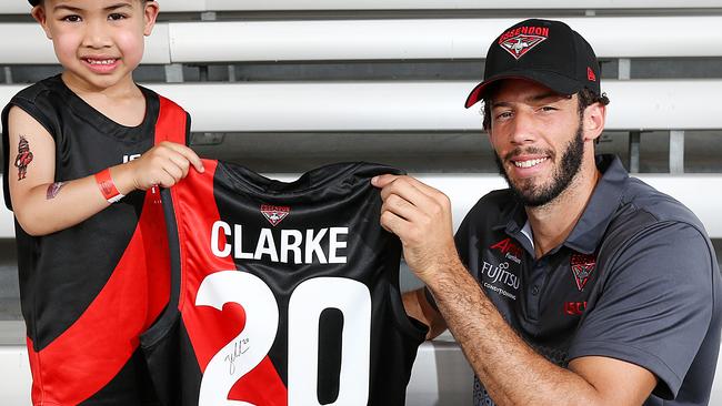 Essendon recruit Zac Clarke is presented with his jumper by young Bomber Eugene. Picture: Ian Currie