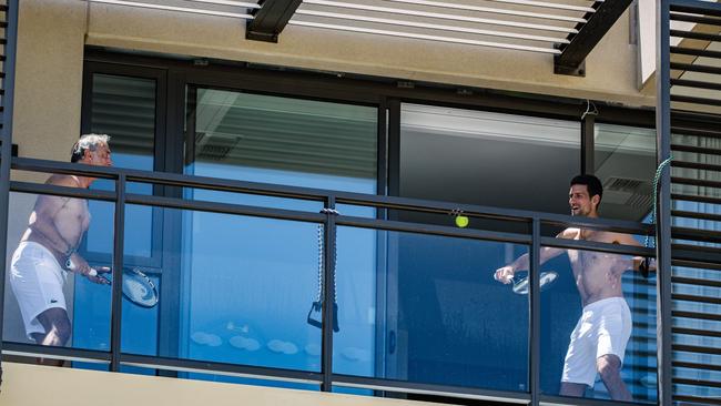 World No. 1 Tennis player Novak Djokovic, right, playing tennis on a balcony where he is quarantined at the M Suites in Adelaide. Picture: Morgan Sette/AFP