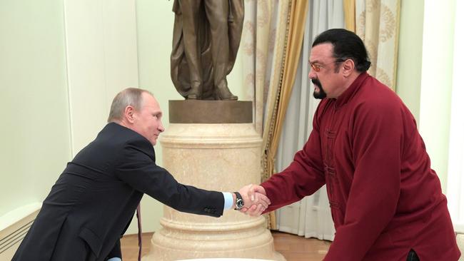 Russian President Vladimir Putin shakes hands with US action hero actor Steven Seagal after presenting him with a Russian passport at the Kremlin in 2016. Picture: AFP Photo / Sputnik / Alexey Druzhinin