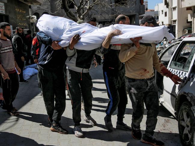 Men carry the body of a Palestinian killed in an early morning incident when residents rushed toward aid trucks in Gaza City. Picture: AFP