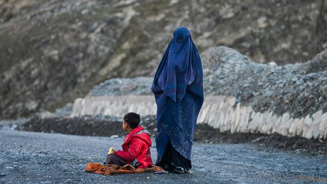 An Afghan burqa-clad woman asks for alms along a street in Badakhshan province in Afghanistan in December. Picture: AFP