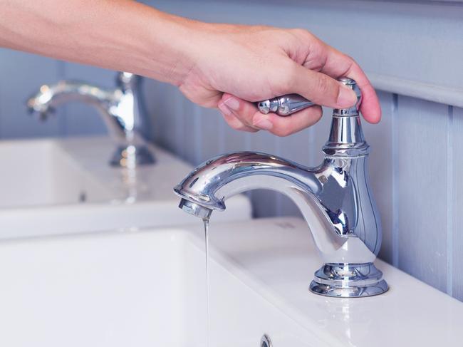 hand man opening silver faucet or water tap with white washing sink in public toilet.