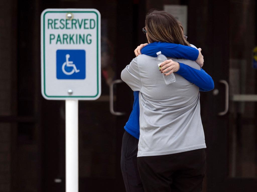 Two people embrace at a reunification centre in the McCreary Community Building after a shooting at the Perry Middle and High School complex. (Photo by Christian Monterrosa / AFP)