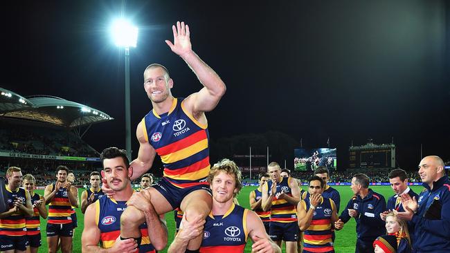 Scott Thompson is chaired off the ground by Crows teammates Taylor Walker and Rory Sloane after playing his 300th AFL game against Collingwood at Adelaide Oval in 2016. Picture: Daniel Kalisz/Getty Images