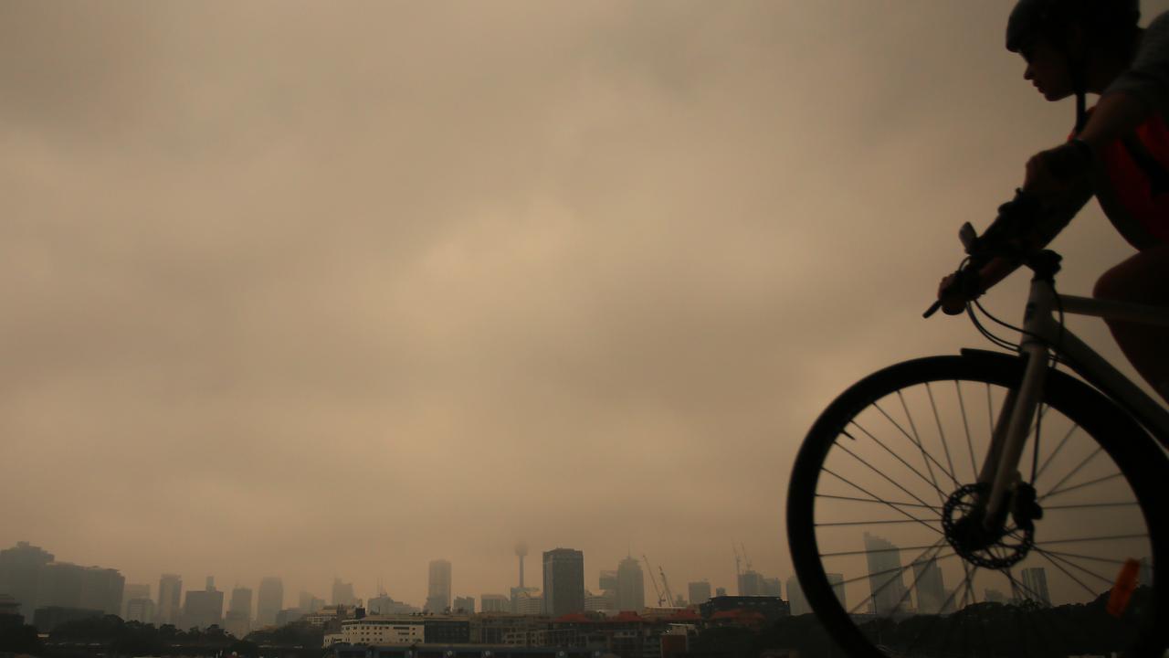 A cyclist rides in Blackwattle Bay as smoke haze from bushfires in New South Wales blankets the CBD in Sydney on Tuesday. Picture: Steven Saphore/AAP