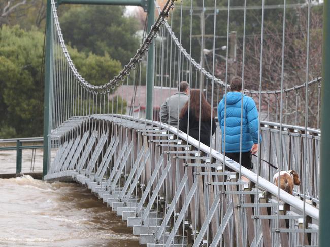 People walk over a pedestrian bridge as the Meander River rises. Picture: BRUCE MOUNSTER