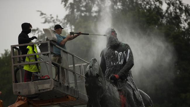 Workers clean graffiti from a statue of Belgium's King Leopold II in Brussels, that was targeted by protesters during a Black Lives Matter demonstration.