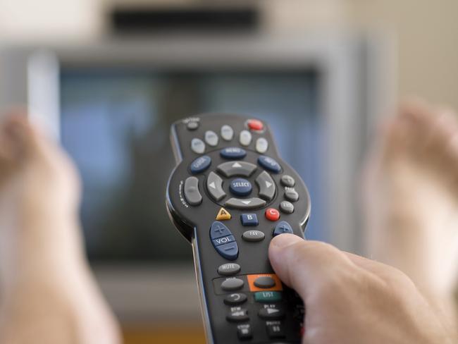 A man watches television and changes channels while relaxing on a Sunday afternoon.