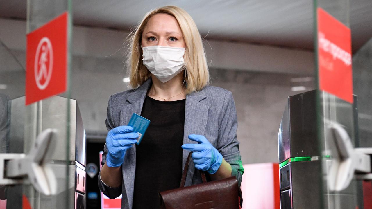 A woman wearing a face mask and gloves walks through ticket gates at Savyolovskaya station on the Moscow metro. Picture: Kirill Kudryavtsev/AFP