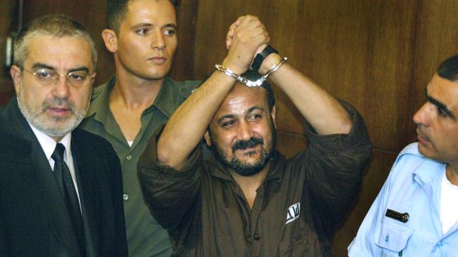 Marwan Barghouti raises his handcuffed hands in the air on the opening day of his court case at Tel Aviv's District Court, August 2002.