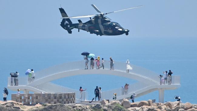 Tourists watch a Chinese military helicopter fly past Pingtan island, one of mainland China's closest point from Taiwan. Picture: AFP