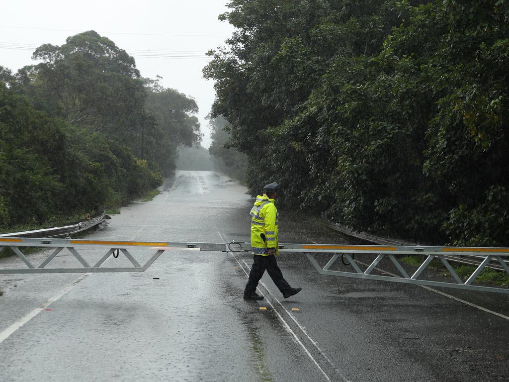 Heavy rain again lashes Sydney , Causing flooding on the Wakehurst Parkway forcing police to close the rd. Police guide the last cars through before shutting the gates . Picture John Grainger