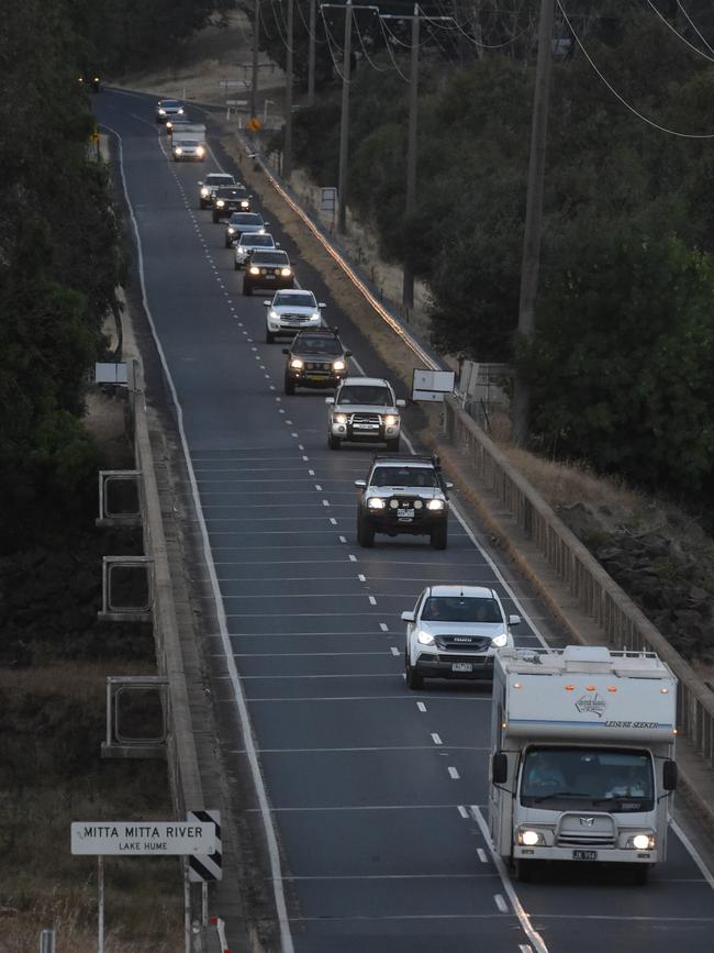 A convoy flees under the protection of fire crews. Picture: Tony Gough