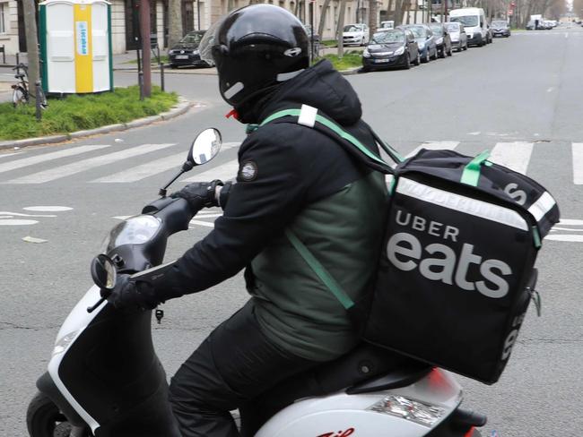 An Uber Eats delivery man rides a moped in Paris on March 22, 2020, as a strict lockdown comes into effect to stop spread of the COVID-19 caused by novel coronavirus in the country prohibiting all but essential outings in a bid to curb coronavirus spread. (Photo by Ludovic MARIN / AFP)