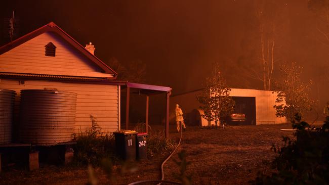 Firefighters work to save the 100-year-old school near Termeil on the Princes Highway. Picture: AAP/Dean Lewins