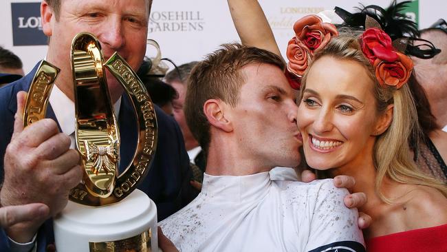 Jockey Ben Melham kisses his partner Karlie Dales as he and trainer Gary Portelli (left) hold the Golden Slipper trophy after winning the Longines Golden Slipper race on She Will Reign during Golden Slipper Day at Rosehill Racecourse in Sydney, Saturday, March 18, 2017. (AAP Image/David Moir) NO ARCHIVING, EDITORIAL USE ONLY