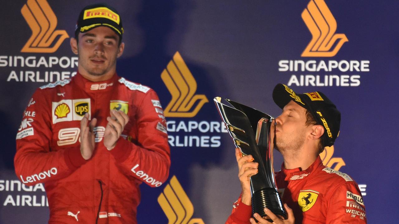 Sebastian Vettel (R) kisses the trophy as Charles Leclerc (L) looks on.