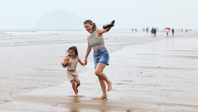 Frankie Hall and her daughter Ellie Hall, holidaying from the UK, beat the rising tide as the skip along the sandbar. Picture: Brendan Radke