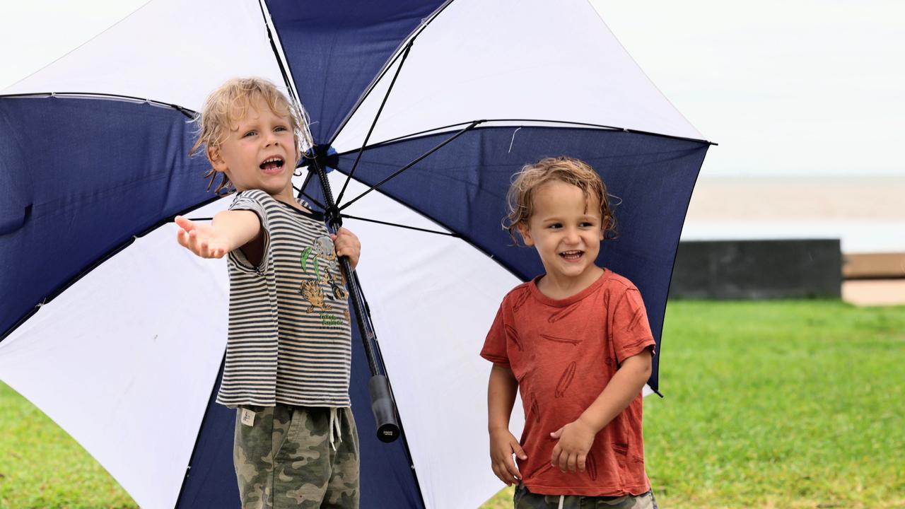 A stubborn monsoonal low pressure system is still lingering over Far North Queensland, bringing widespread rain and wet weather to Cairns. Mooroobool brothers Tucker Podhaczky, 4, and Sunny Podhaczky, 2, were wondering if the weather would ever improve during a walk along the Cairns Esplanade with their father on Tuesday. Picture: Brendan Radke