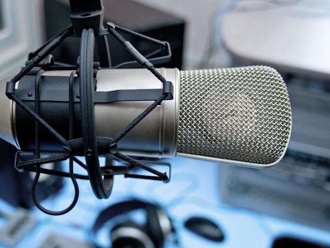 Large microphone hanging over radio station control panel.
