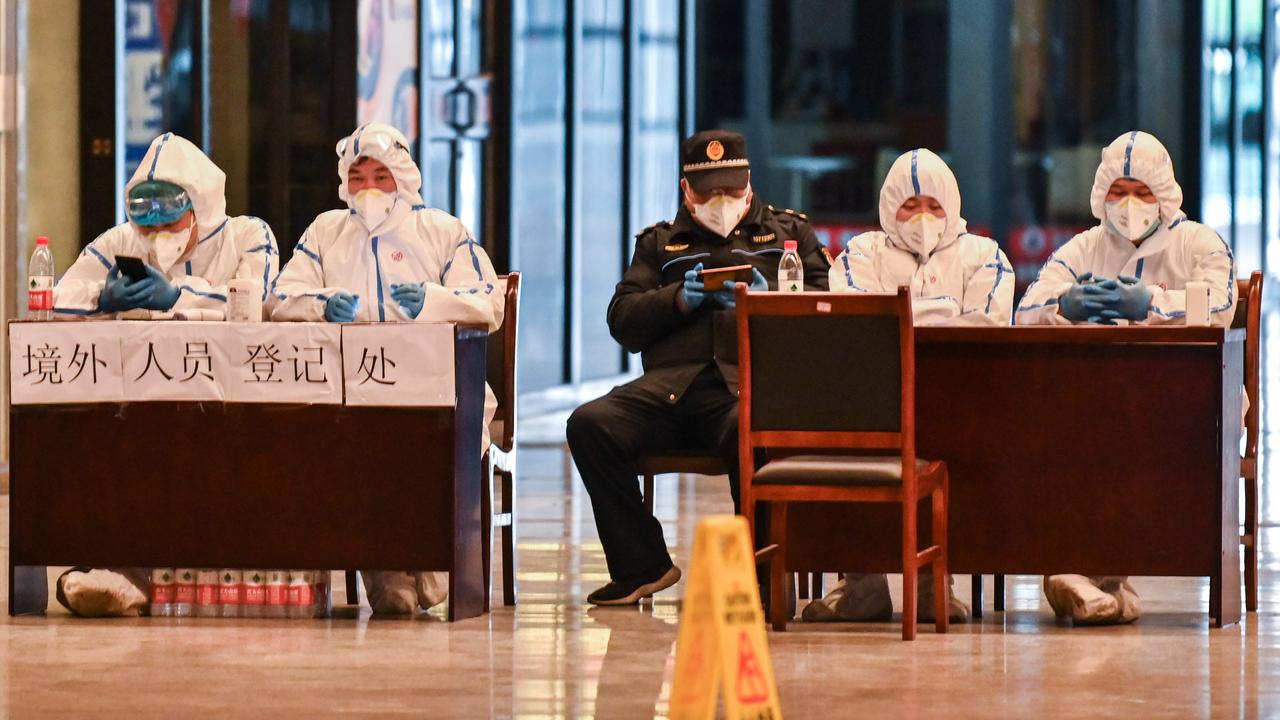 Workers in protective gear wait for passengers arriving at the railway station in Wuhan, China. Photo: AFP