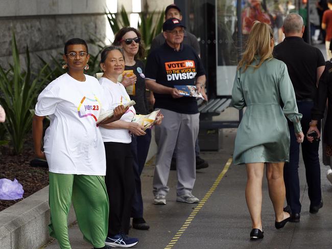 Yes and No campaigners hand out leaflets as members of the public vote at Brisbane City Hall on the first day of early voting for the referendum. Picture: NCA NewsWire/Tertius Pickard