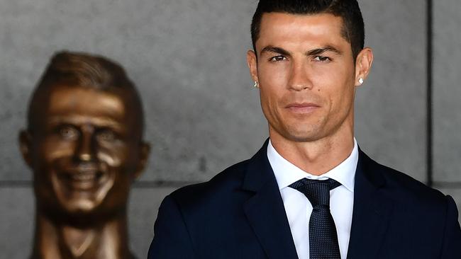 Portuguese footballer Cristiano Ronaldo stands near a bust presented during a ceremony.