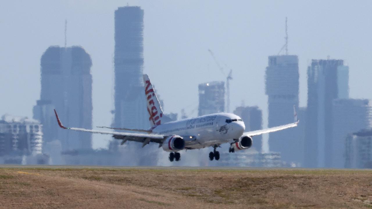 Plane landing at Brisbane airport with the city in the background. Picture: Liam Kidston